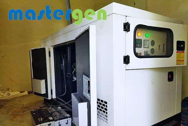 INDONESIA, JAWA TIMUR - A diesel-powered industrial generator with its access panel open during a maintenance check. The control panel indicators are illuminated, and the external battery is visible on the floor. Suitable for themes of power supply, backup energy systems, industrial equipment, engineering, and facility operations.